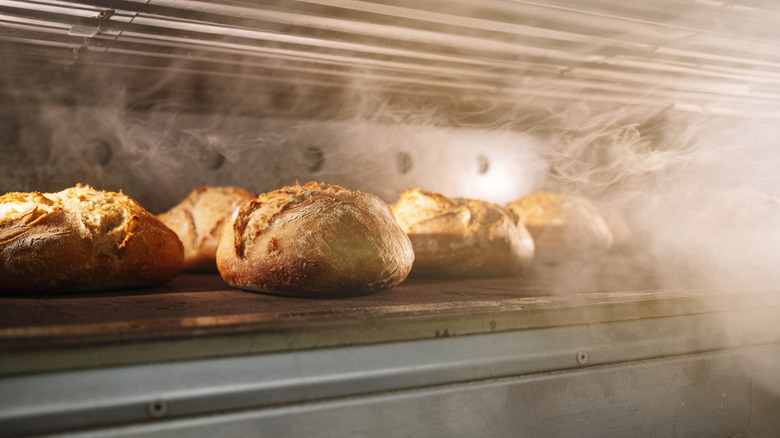 Round loaves of bread steaminig inside an oven