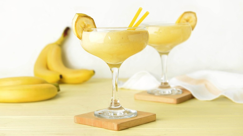 two yellow blended drinks with banana garnish