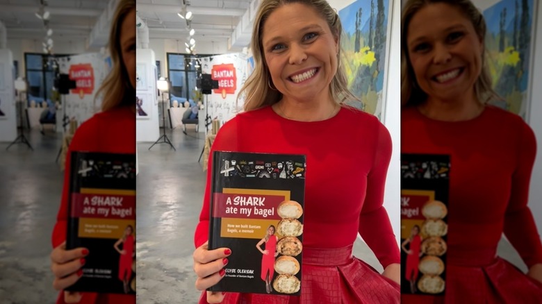 Elyse Oleksak smiling with copy of A Shark Ate My Bagel book