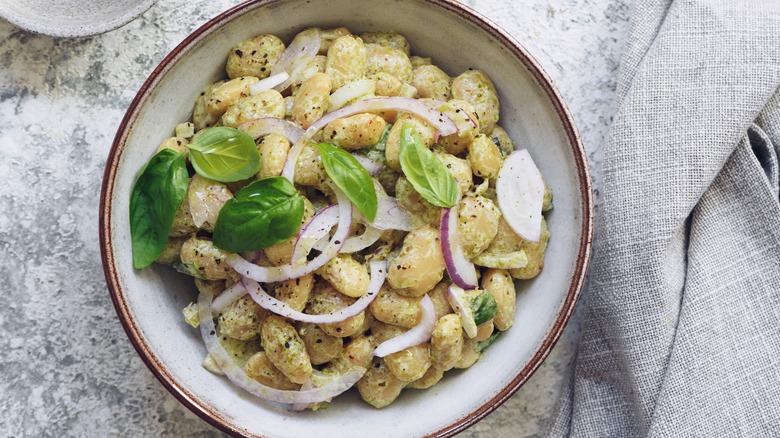 Butter beans in creamy pesto sauce with red onions and basil leaves