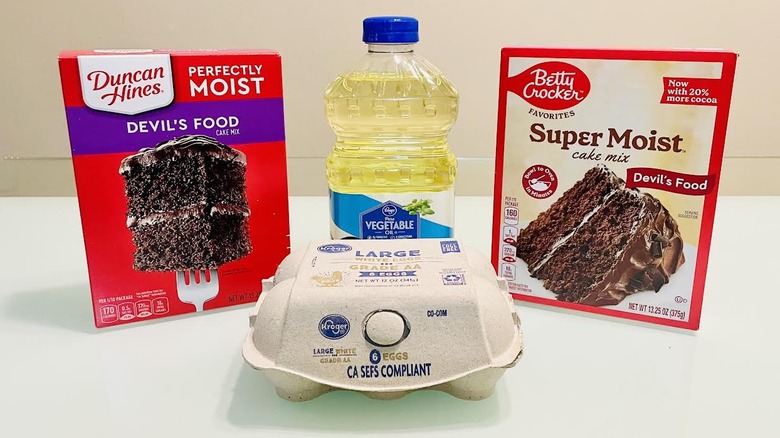 Boxes of Duncan Hines and Betty Crocker Devil's Food cake mix with eggs and oil