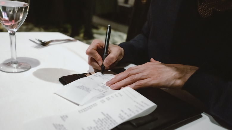 Signing the bill at the end of a restaurant dinner