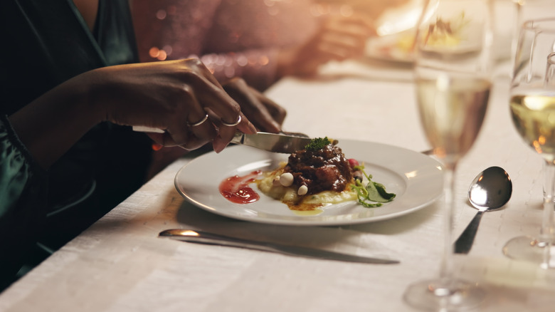 Woman cutting meat at high-end restaurant