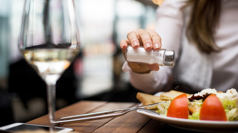 Adding table salt to restaurant salad