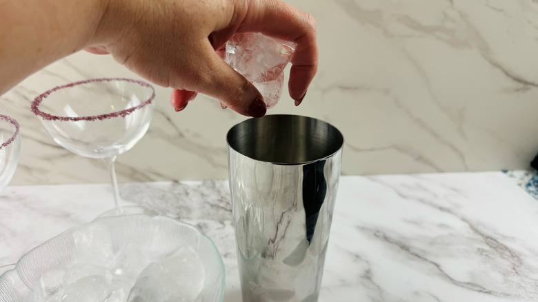 hand adding ice to shaker