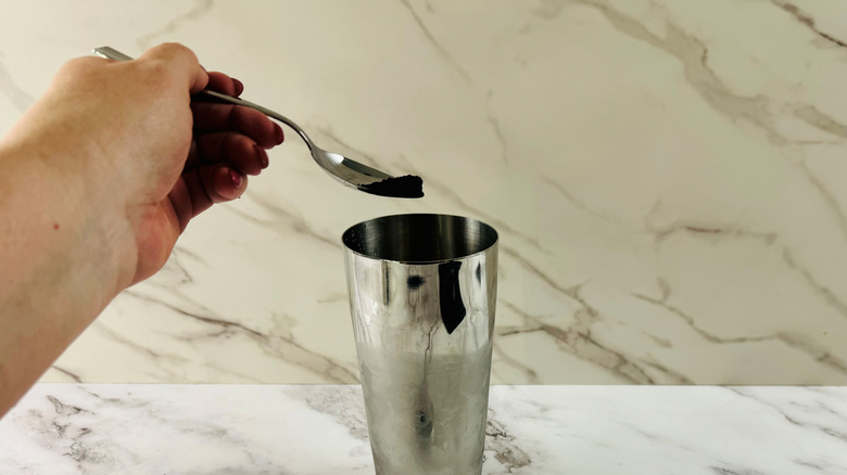 hand spooning charcoal into shaker