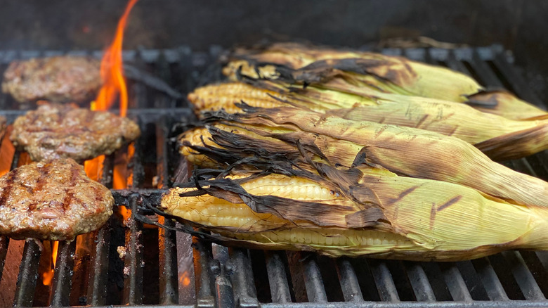 Corn in husks and burgers on grill