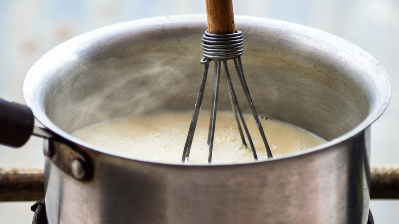 milk boiling over a steel pan on the stovetop