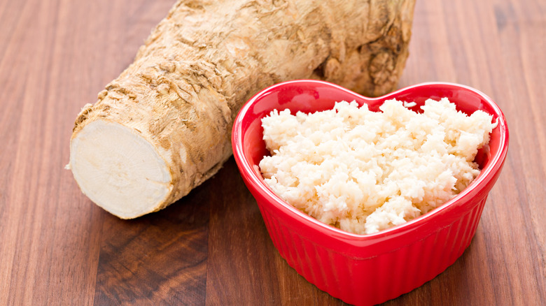 grated horseradish in a red bowl with whole horseradish