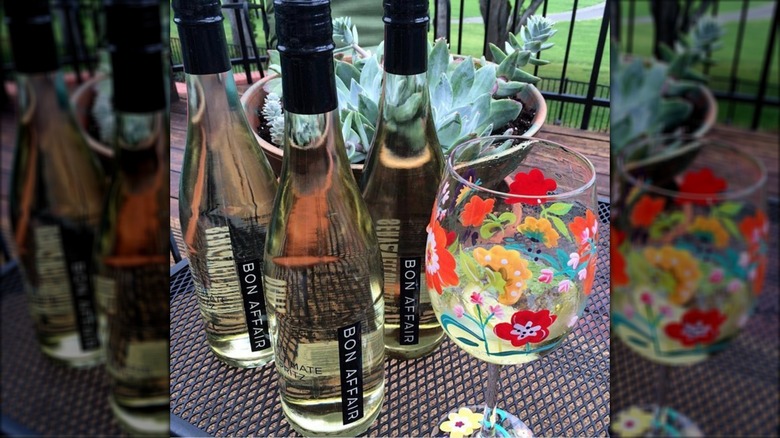Bottles of Bon Affair next to floral wine glass