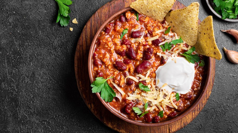 bowl of turkey chili with pinto beans, tortilla chips, and sour cream