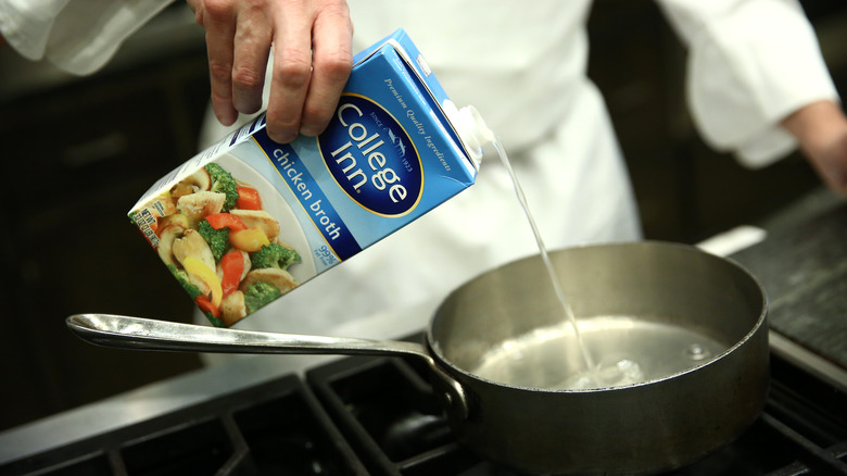 Boxed chicken broth pouring into pot