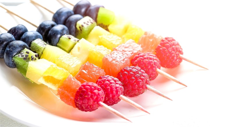 Fresh fruit kebabs on white background