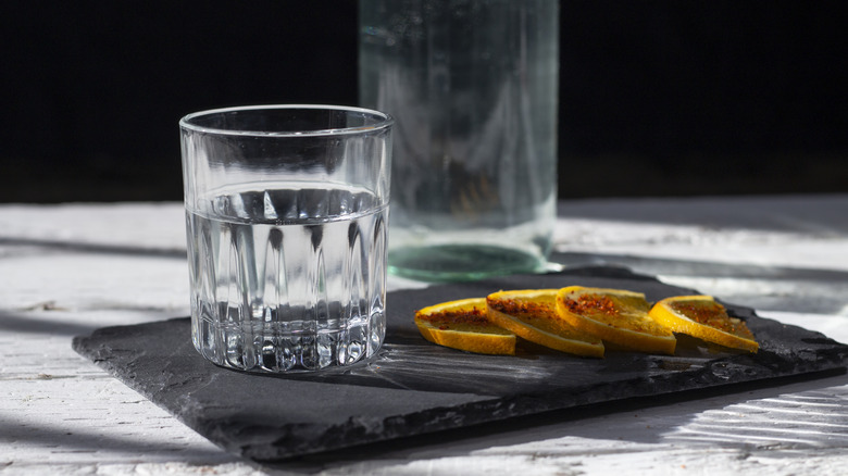 Clear liquor in glass next to spiced orange slices