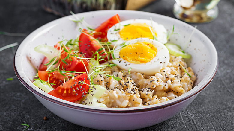 Bowl of oatmeal with egg, tomatoes, and cucumber