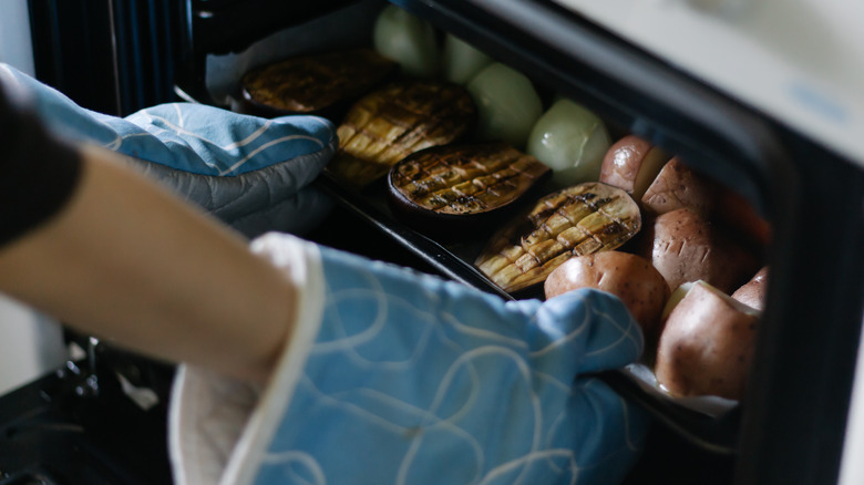 A pan full of broiled vegetables being removed from the oven