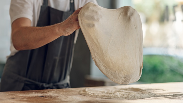 Pizza chef hand stretching dough