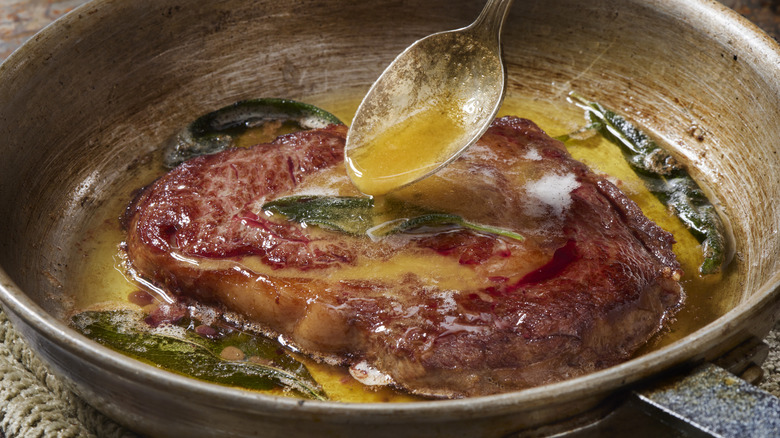 Steak being basted with butter and sage