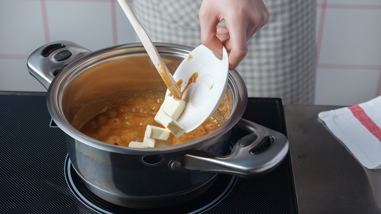 Adding butter to a pot of caramel sauce