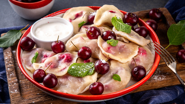 A plate of pierogis with cherries on top