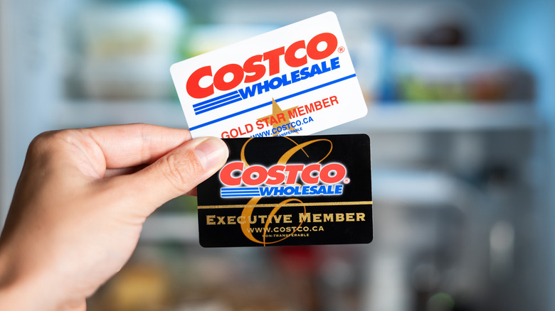 Hand holding two Costco membership cards