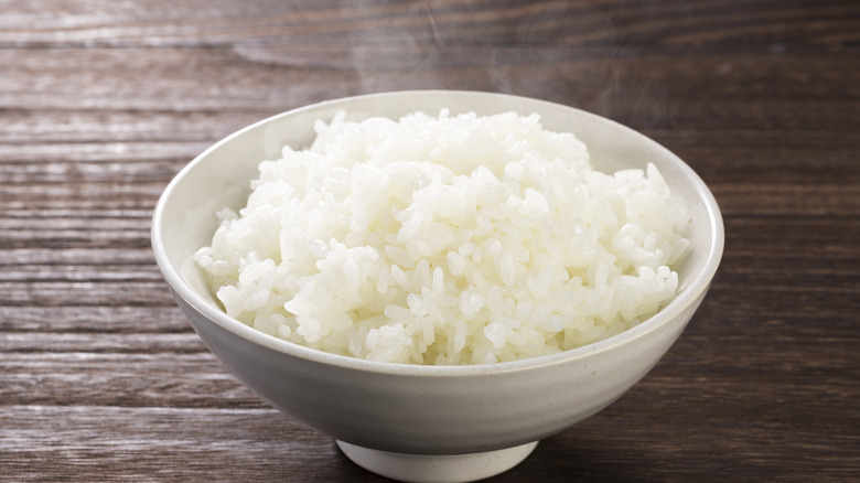 white rice steaming in a hot bowl on wooden surface