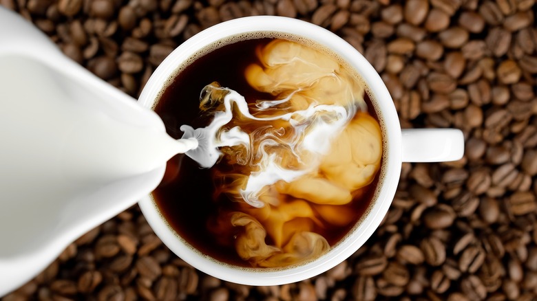 Milk being poured into a cup of coffee