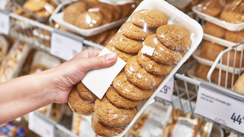 Someone holds a package of oatmeal cookies at a bakery or grocery store