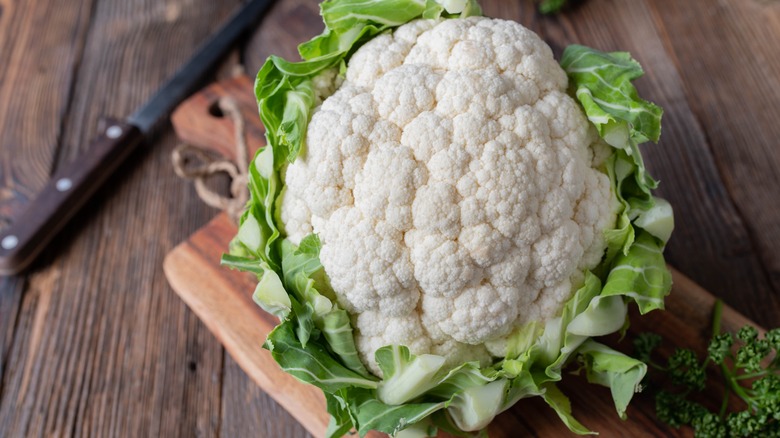 A whole cauliflower on a wooden board