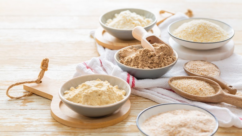 Various types of flour in bowls on wood table