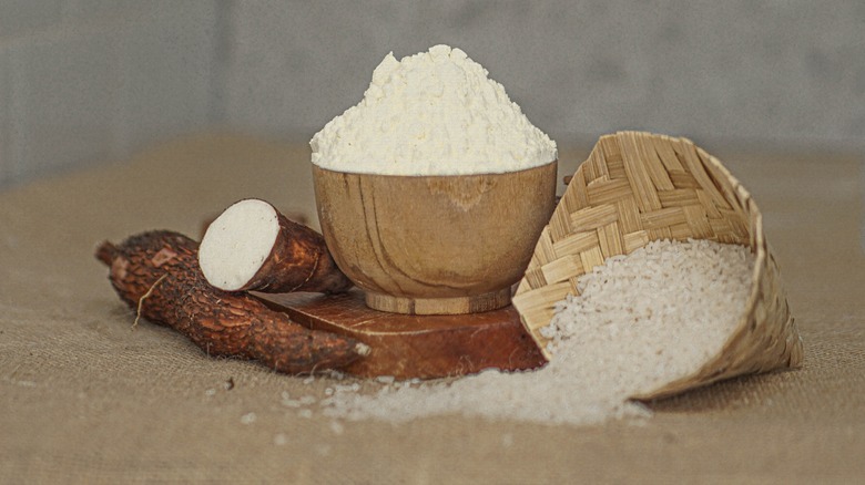 Cassava flour in wood and wicker baskets next to cassava root