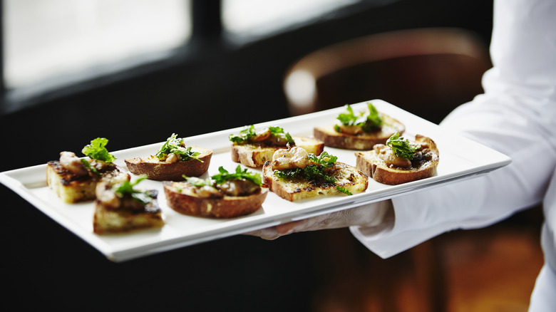 server holding tray of canapés