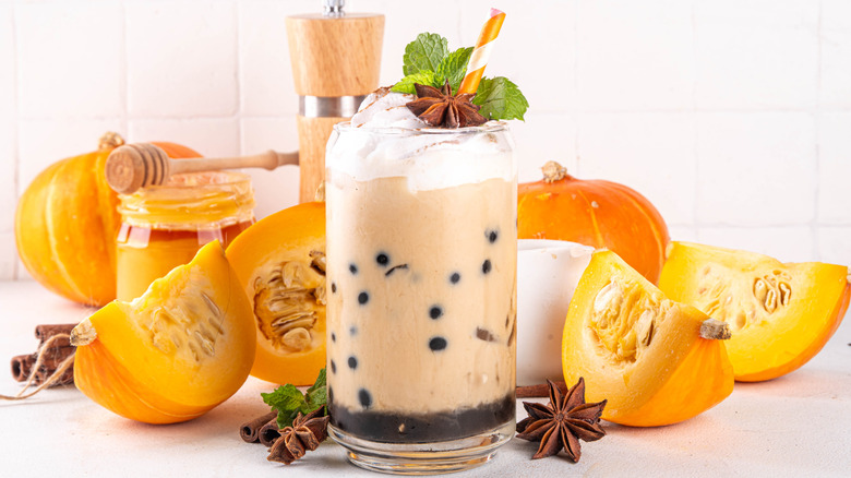 Pumpkin chai bubble tea with tapioca pearls, surrounded by pumpkin wedges