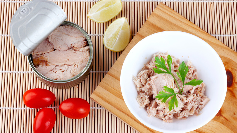 Open can of tuna next to a bowl of tuna