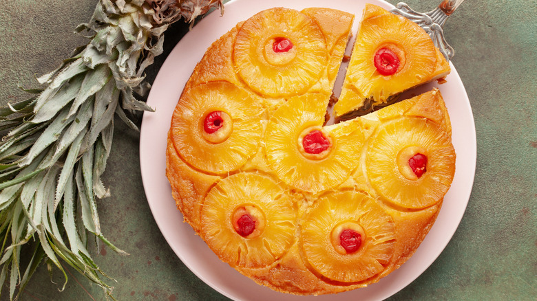 A pineapple upside down cake with pineapple rings and candied cherries