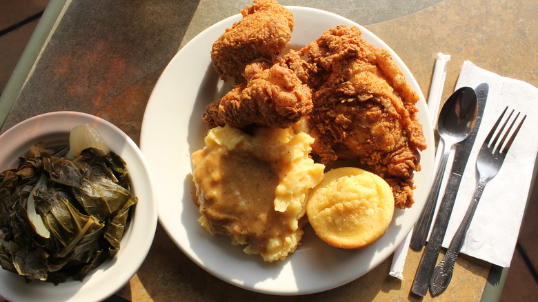 fried chicken, mashed potatoes, corn bread served alongside a bowl of collard greens