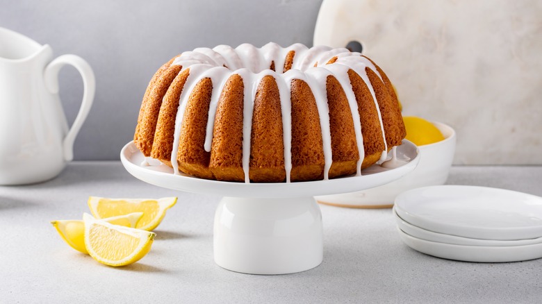 Bundt pound cake with glaze on white cake stand with lemons