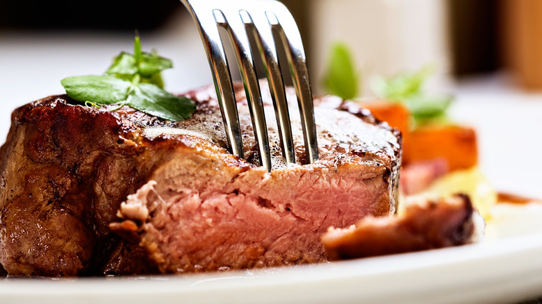 Fork cutting into beef filet