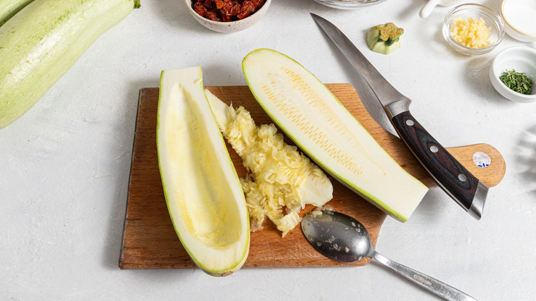 Cored zucchini halves on a cutting board.