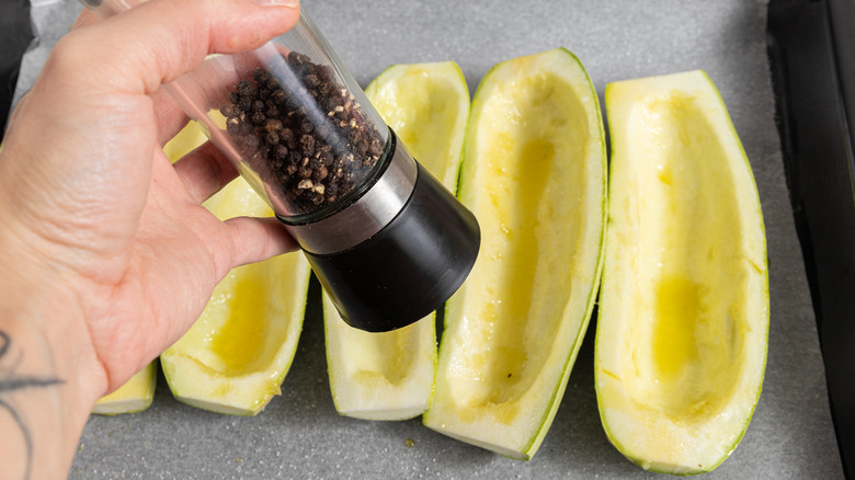 Grinding black pepper over zucchini haves.