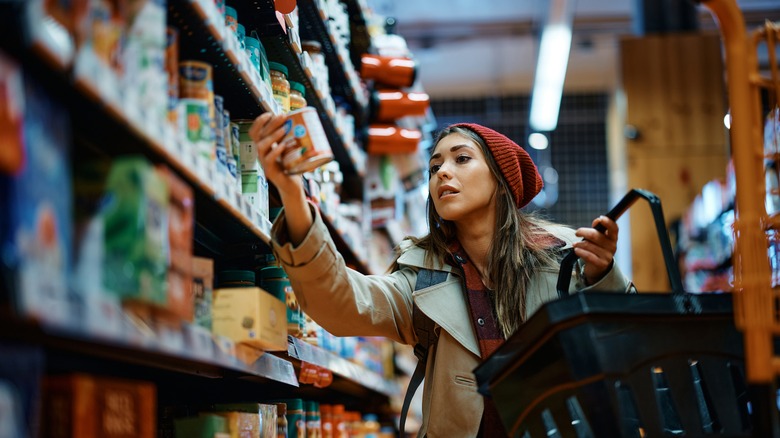woman examines can at grocery store