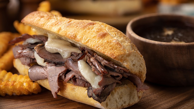 french dip sandwhich with bowl of au jus and french fries