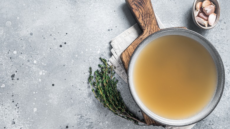 chicken stock in a pot on wooden board