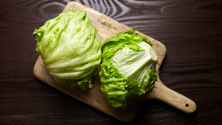 Two heads of iceberg lettuce on a cutting board