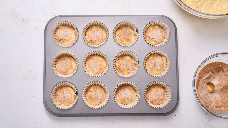 adding cinnamon sugar to muffins