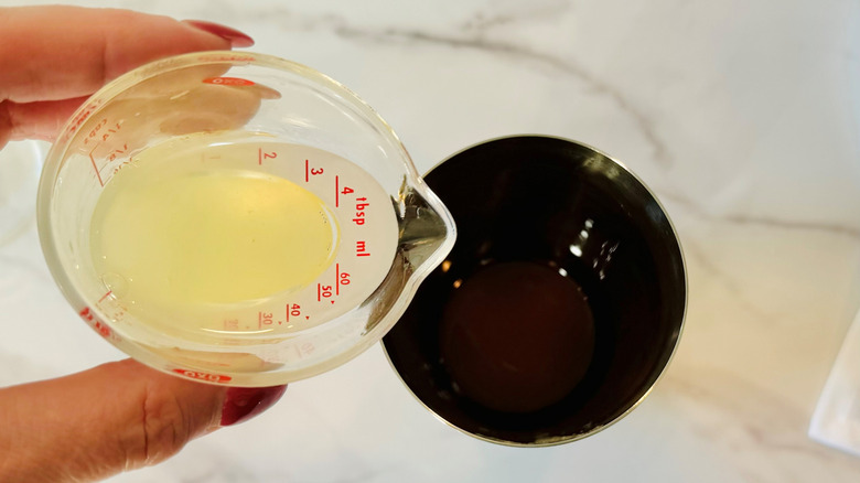 hand pouring liquid into shaker