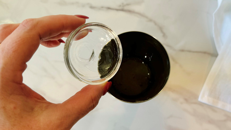 hand pouring liquid into shaker