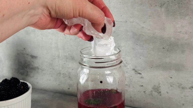 Hand adding ice cubes to glass jar