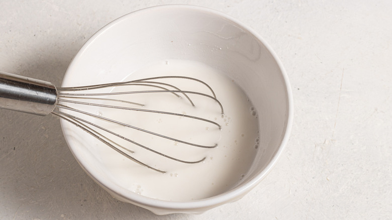A whisk inside of a bowl with white liquid