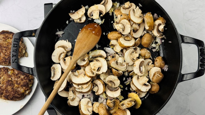 stirring sliced mushrooms shallots and garlic in skillet